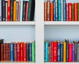 assorted-title book lot placed on white wooden shelf
