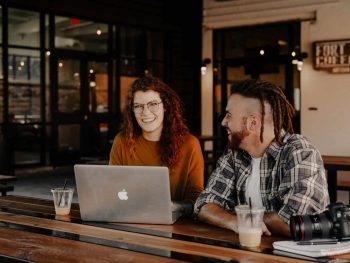 man and woman sitting in front of silver macbook